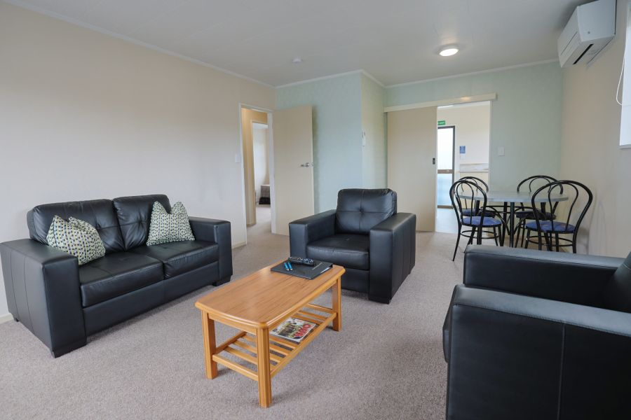 Motel lounge with leather sofa, armchairs, wooden coffee table and dining chairs
